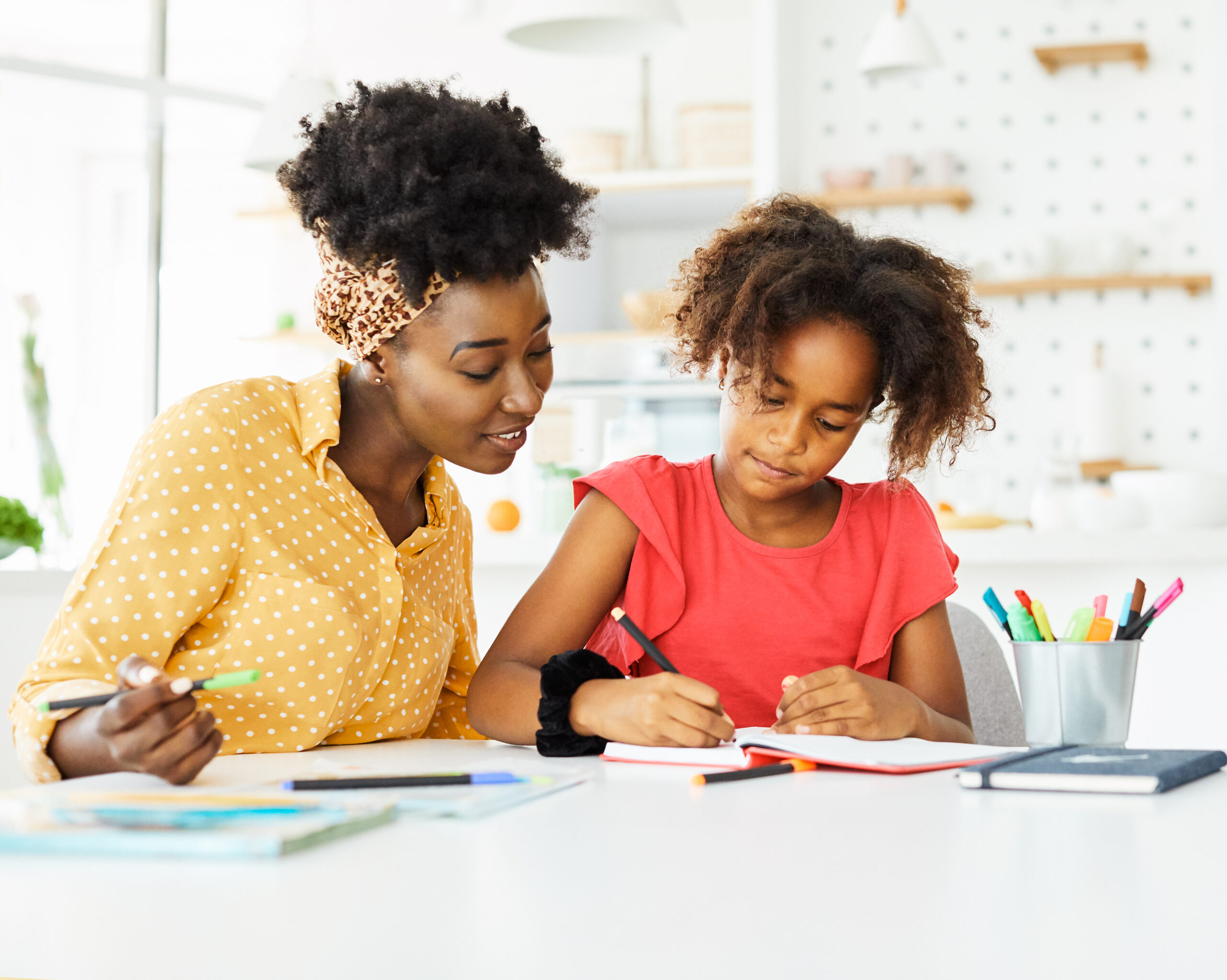 mother teaching daughter and helping her with homework at home
