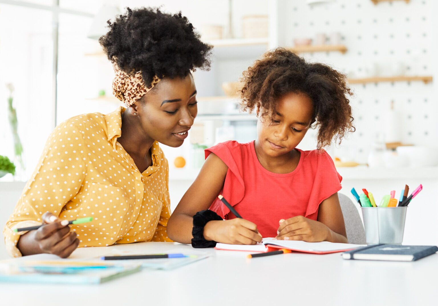 mother teaching daughter and helping her with homework at home