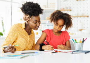 mother teaching daughter and helping her with homework at home